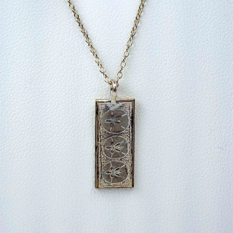 Small vertical rectangular sterling silver pendat with the impresison of 3 small sand dollars on it, with a sterling silver chain