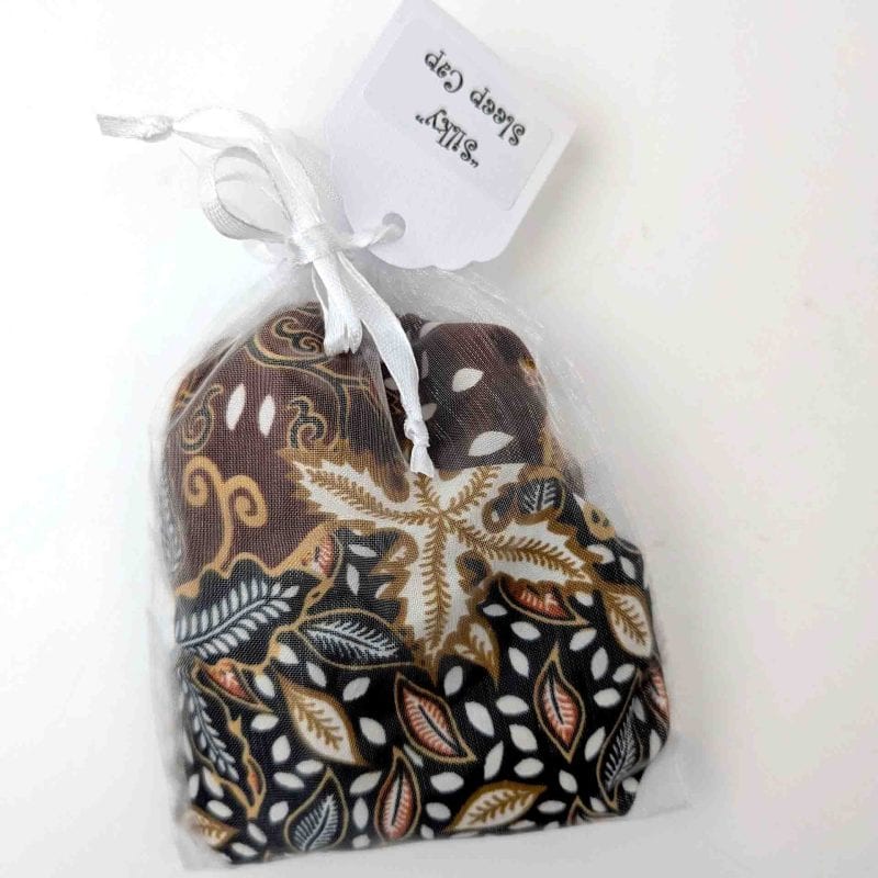 Sleep cap with brown and black background with white and red leaves pattern in a see through bag