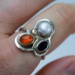 Sterling Silver Garnet Pearl and Amber Ring (1) Sterling Silver Garnet Pearl and Amber Ring This sterling silver ring combines three different stones in one compact design. The deep red garnet, soft white pearl and warm amber create a strong contrast in colour and surface, giving the piece a distinctive and balanced look. An individual handmade ring with a decorative but still easy to wear character.