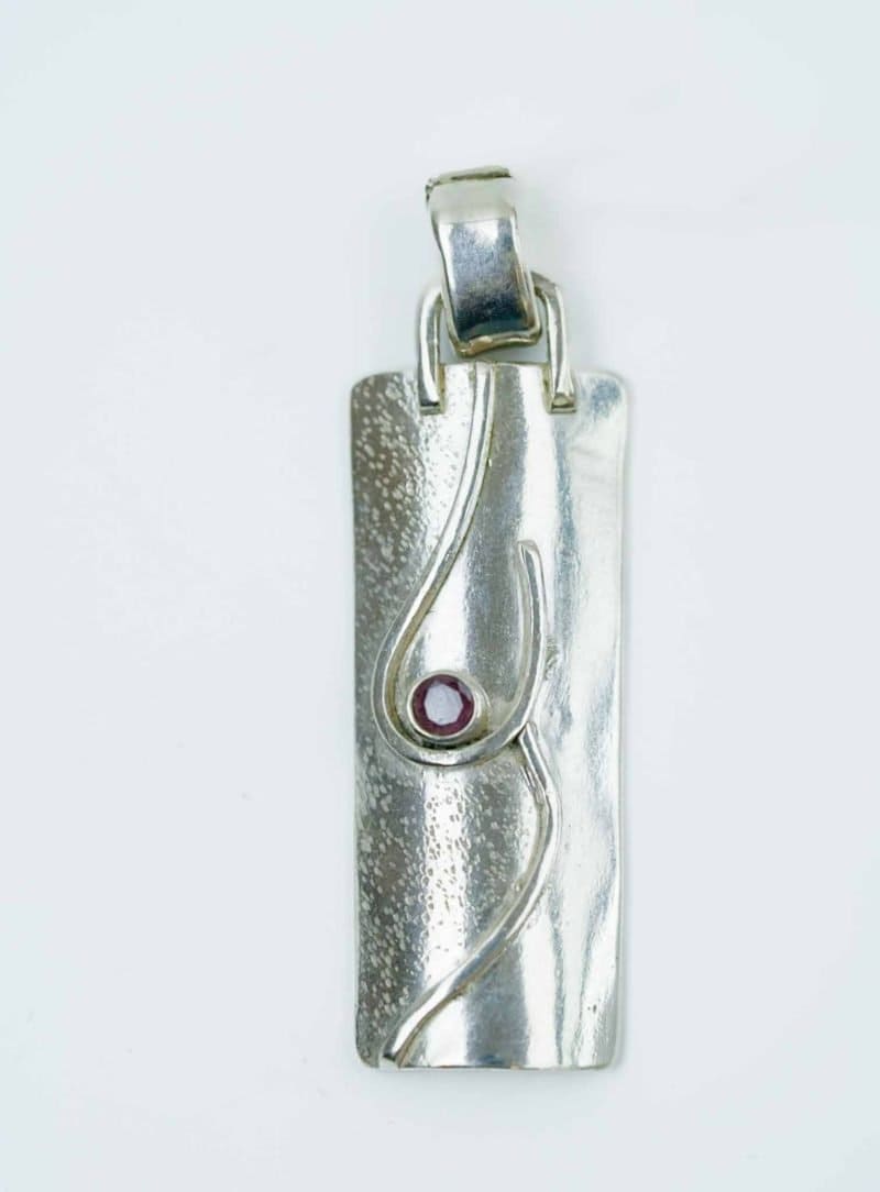 This pendant is made from sterling silver and set with a garnet in a deep red shade.