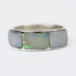 Close-up of a sterling silver ring featuring three rectangular solid opal inlays. Each opal displays a luminous play of colour with flashes of green, blue, and red across a soft white base, highlighting the ring’s polished silver setting against a plain white background.