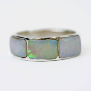 Close-up of a sterling silver ring featuring three rectangular solid opal inlays. Each opal displays a luminous play of colour with flashes of green, blue, and red across a soft white base, highlighting the ring’s polished silver setting against a plain white background.