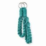 Two handcrafted teal macramé wristlets keychains made from thick braided cotton cord, featuring a silver metal ring at the top. The wristlets are displayed against a clean white background with soft, even lighting and a subtle shadow beneath, highlighting its texture and vibrant sea‑green colour.
