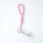 A handcrafted pink macramé wristlet keychain made from thick braided cotton cord,