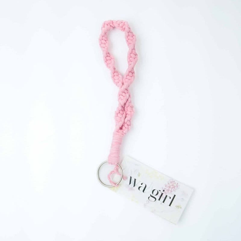 A handcrafted pink macramé wristlet keychain made from thick braided cotton cord,