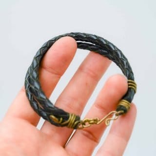 A black braided leather bracelet with brass wire wraps and a hook clasp by Oswaldo Paz local Fremantle Artisan