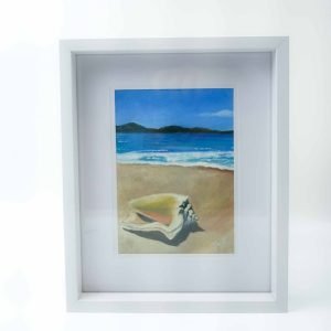 Framed original oil painting by Julie Eaton depicting a serene coastal scene with a large seashell resting on sandy beach in the foreground, gentle waves rolling onto shore, and distant green headlands under a bright blue sky.