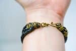multi strand leather woven bracelet (3) A black braided leather bracelet with brass wire wraps and a hook clasp by Oswaldo Paz local Fremantle Artisan