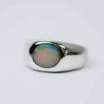 Solid white oval Opal with reds, green and blues in a polished sterling silver bezel