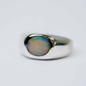 Solid white oval Opal with reds, green and blues in a polished sterling silver bezel