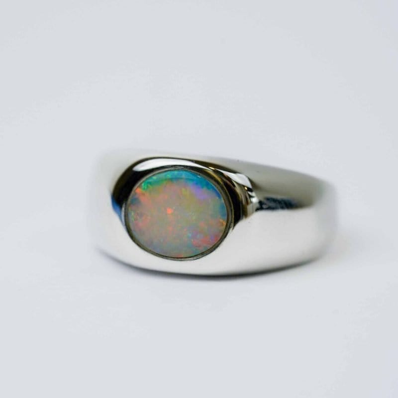Solid white oval Opal with reds, green and blues in a polished sterling silver bezel