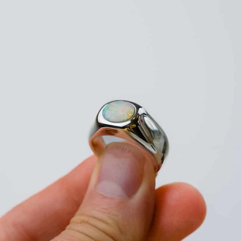 solid white opal with reds, greens and blues in a sterling silver bezel