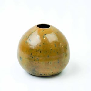 A small, handcrafted round vase made from Klamath clay, featuring a smooth glossy surface with an ochre-brown base and subtle blue-green speckles. The vase has a narrow opening at the top and a gentle stripe detail, finished with an opal lustre glaze that reflects light softly against a plain white background.