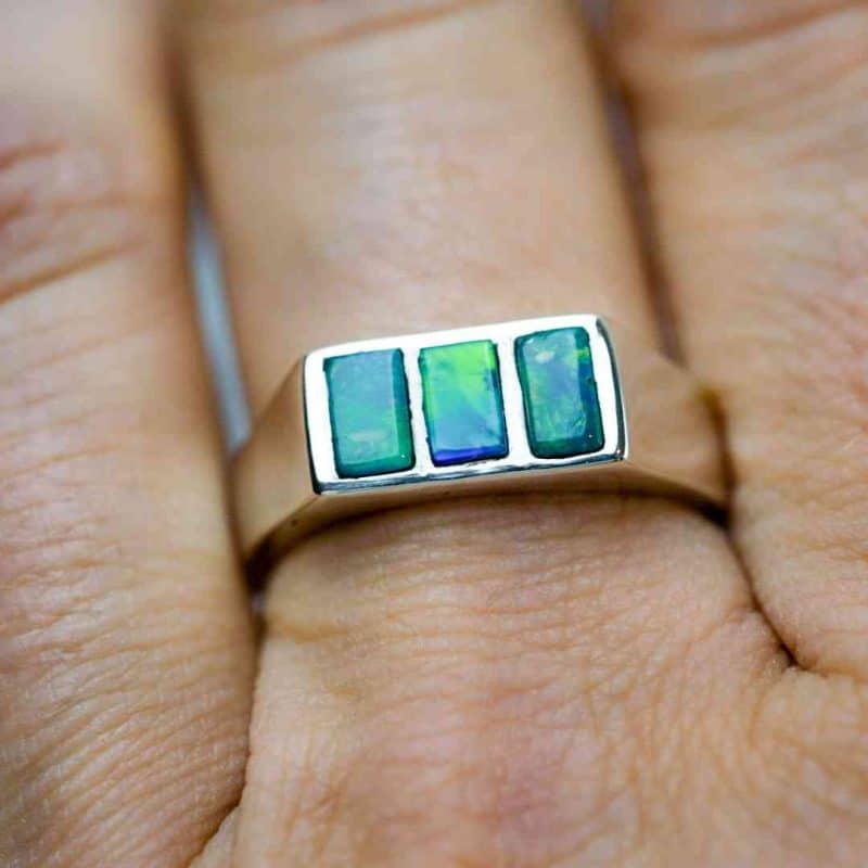 A close up of the opal ring. The ring is being worn on the finger of a light-skinned woman