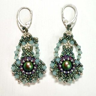 A pair of intricate beadwork earrings. The earrings are green in colour and resemble a ballerina with their arms in first position and a big tutu