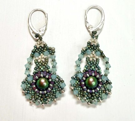 A pair of intricate beadwork earrings. The earrings are green in colour and resemble a ballerina with their arms in first position and a big tutu