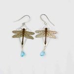 The dragonfly earrings lay flat on an off-white background