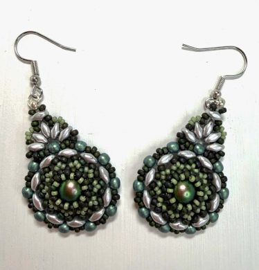 A pair of green earrings on a white background. The earrings are circular and made from intricate beading