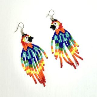 A pair of earrings made from intricate beadwork. The earrings resemble a mccaw, with their bright colouring and features clearly displayed against a whtie background