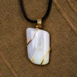 Opal and gold wire pendant (2) The opal sits on a brown fabric background.