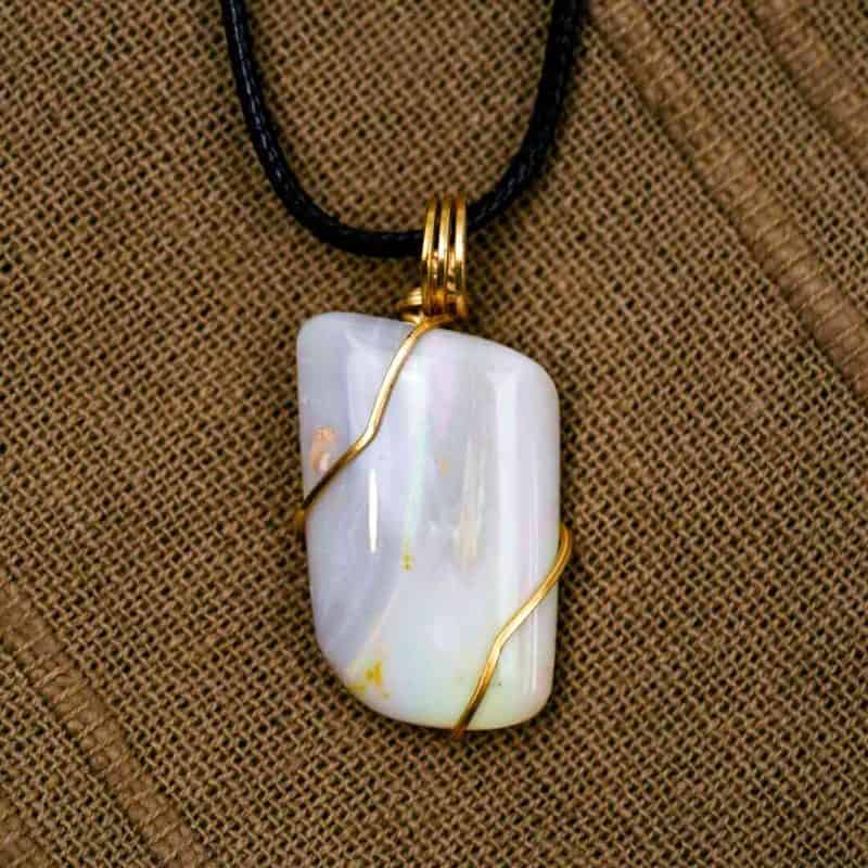 The opal sits on a brown fabric background.