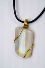 Opal and gold wire pendant (3) A large white opal pendant is wrapped in golden wire and attached to a black wax necklace. The open shimmers in shades of green, purple, and orange
