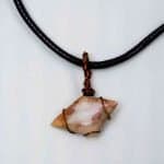 Opal wire pendant, antique bronze (1) A unique trapezium-shaped opal with red hue is wrapped in fine wire and attached to a black wax necklace loop. The pendant lays flat on a white background