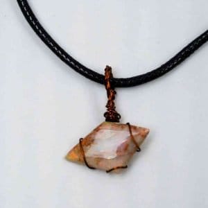 A unique trapezium-shaped opal with red hue is wrapped in fine wire and attached to a black wax necklace loop. The pendant lays flat on a white background