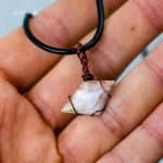 Opal wire pendant, antique bronze (3) The opal pendant layson an open palm, the person's skin is pinkish in colour.