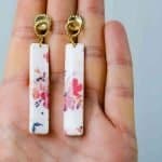 Pink flower drop earrings (3) The polymer clay earrings lay on an open palm, displaying the approximate 6cm length.