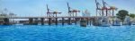 A large rectangular painting of the Swan River in Fremantle. In the foreground the blue waters of the Swan River sparkle in the sun. The Freo Old Bridge sits in the mid-ground with the iconic bright red and orange cranes in the distance.
