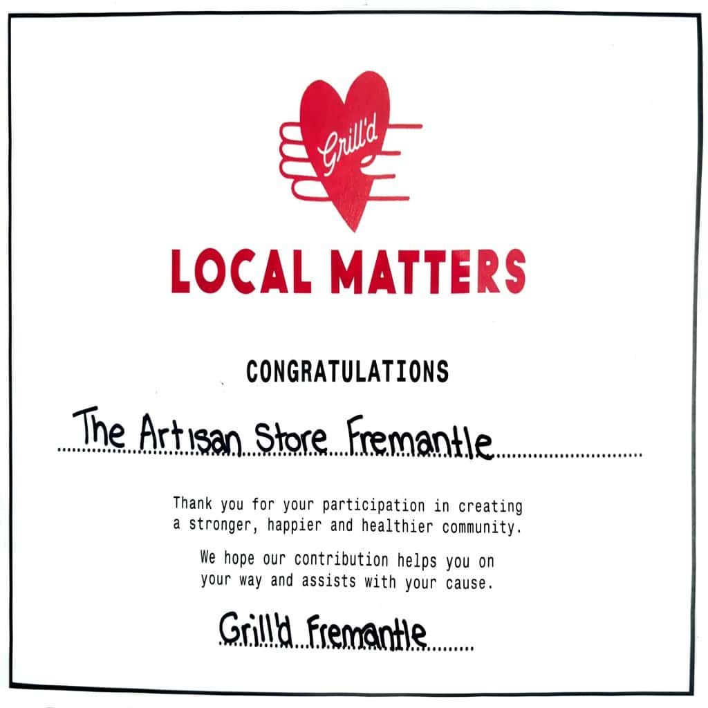 A certificate from Grill’d Fremantle’s Local Matters initiative. The design features a red heart logo with the word “Grill’d” in white script at the top, followed by bold text reading “Local Matters.” Below, the certificate congratulates The Artisan Store Fremantle for participating in building a stronger, happier, and healthier community. The message expresses appreciation and notes that Grill’d’s contribution aims to support the store’s cause. The certificate is signed “Grill’d Fremantle” in handwritten text.