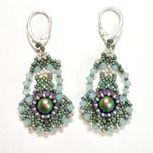 A pair of handcrafted beaded earrings featuring an intricate teardrop design. Each earring has a shimmering iridescent centre bead surrounded by small glass beads in shades of sage green, lilac, and pearl. The earrings are finished with silver lever-back hooks and arranged against a plain white background, highlighting their detailed texture and elegant craftsmanship.