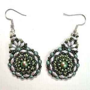 A pair of handcrafted beaded earrings with a teardrop shape, featuring a shimmering iridescent green centre surrounded by intricate layers of small glass beads in shades of sage, silver, and dark olive. The earrings are finished with silver hooks and displayed against a plain white background, highlighting their detailed texture and elegant artisan design.