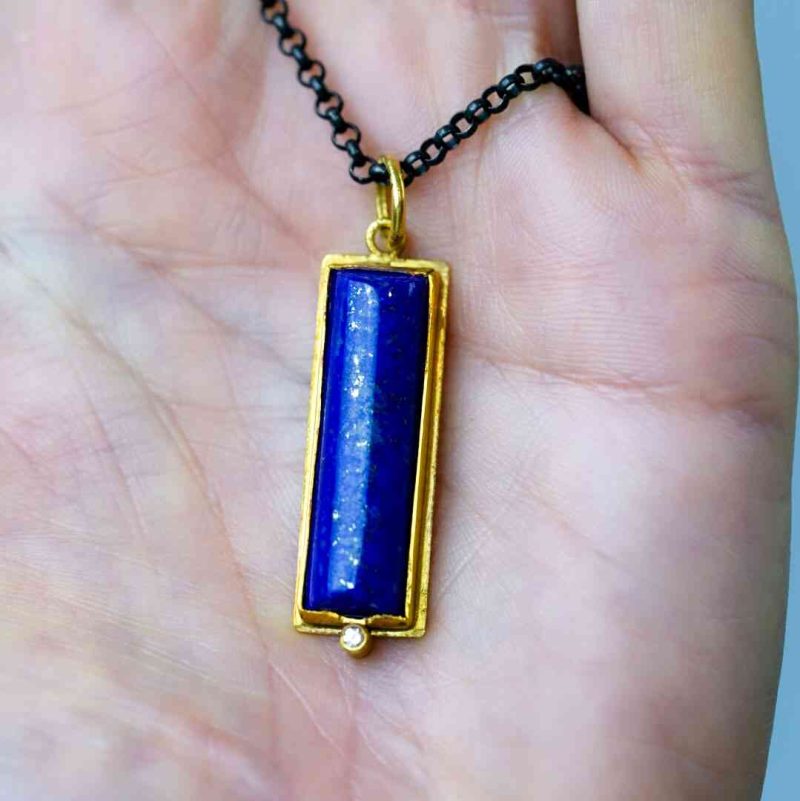 The lapis lazuli pendant rests in the palm of a fair-skinned woman.