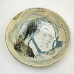 A large cermaic bowl decorated with abstract blue glaze. The bowl is viewed from the top down showing the interior of the bowl, and sits on a white background