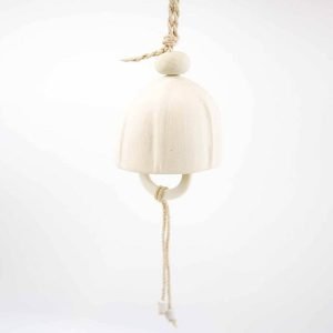 A handcrafted ceramic hanging bell with a smooth, matte ivory finish, suspended by a braided jute rope. The bell has a rounded dome shape, and a long hanging cord beneath it ending in two small matching white ceramic beads, set against a plain white background.