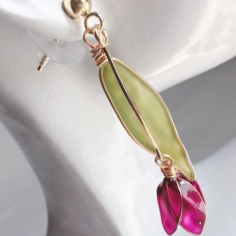 The purple variation of the tulip earrings hang from the ear of a mannequin head