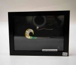 A black frame holding a silver sculpture of a wave. The piece is minimal, just one wave in the centre of the frame.