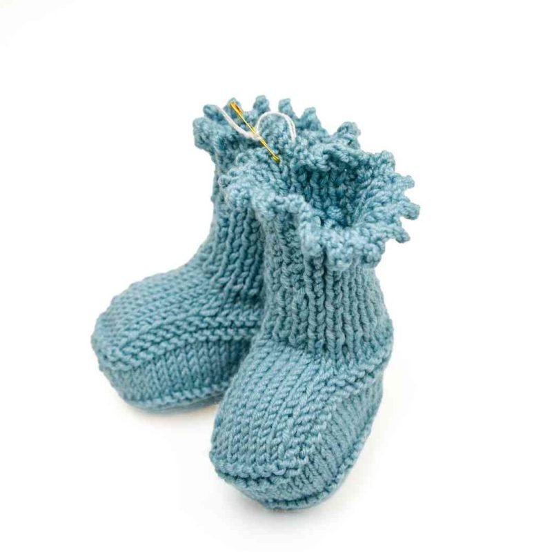 A pair of hand knitted blue baby booties with ruffled top.