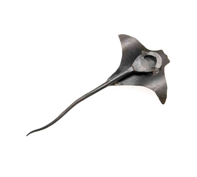 The metal eagle ray is flipped to show it's underside, revealing that it is a bottle opener