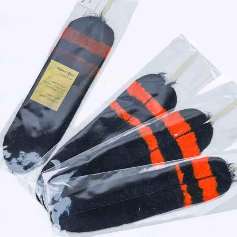 Four hand-felted feathers are splayed on a white background. The feathers are mainly black, with two red stripes at the bottom, resembling the feather of a red tail cockatoo