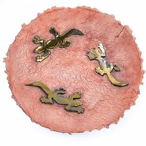 A downwards image of a stoneware oxidised bowl depicting 3 golden lizards